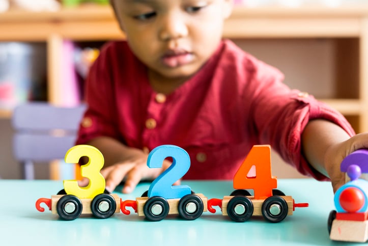 Little boy with autism playing mathematics wooden toy at daycare
