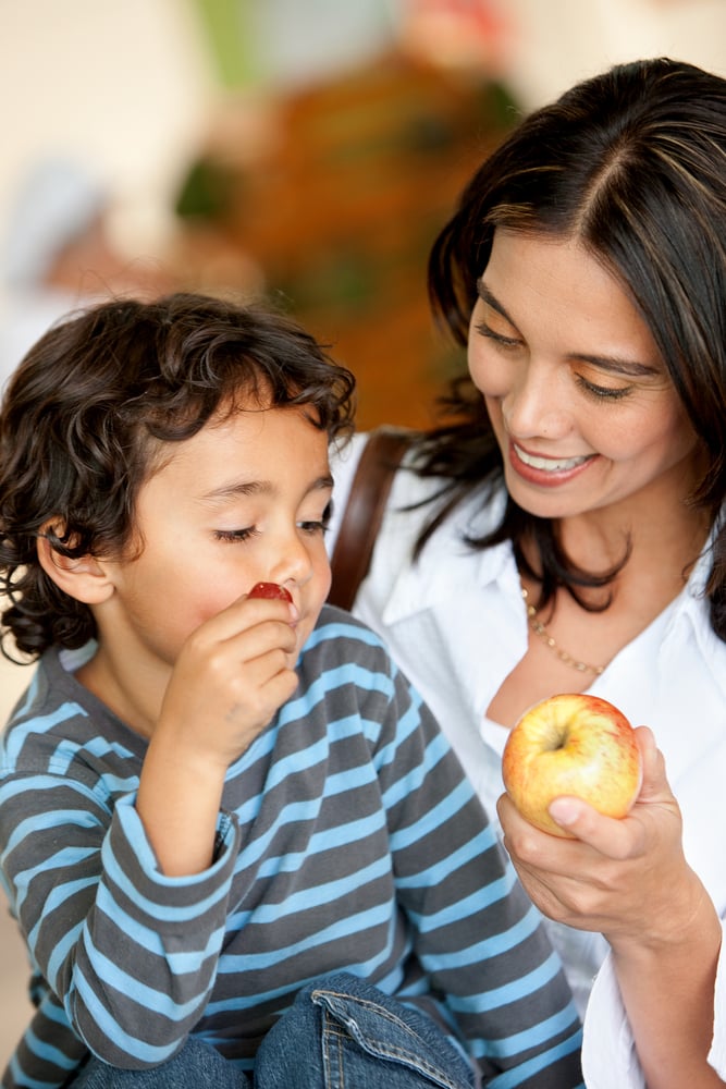 Woman and son at a supermarket eating fruits