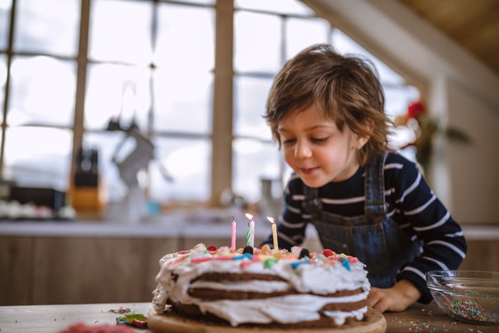 Boy With Autism Blowing Birthday Candles at Home